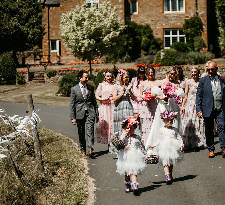 Bridal party with bridesmaids in mismatched dresses, the flower girls in tulle white dresses and flower crowns with father of the bride 