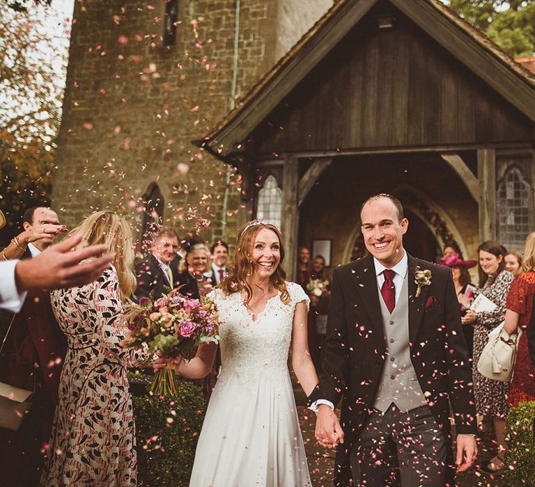 The bride and groom exit from their ceremony to pink confetti from Shropshire Petals 