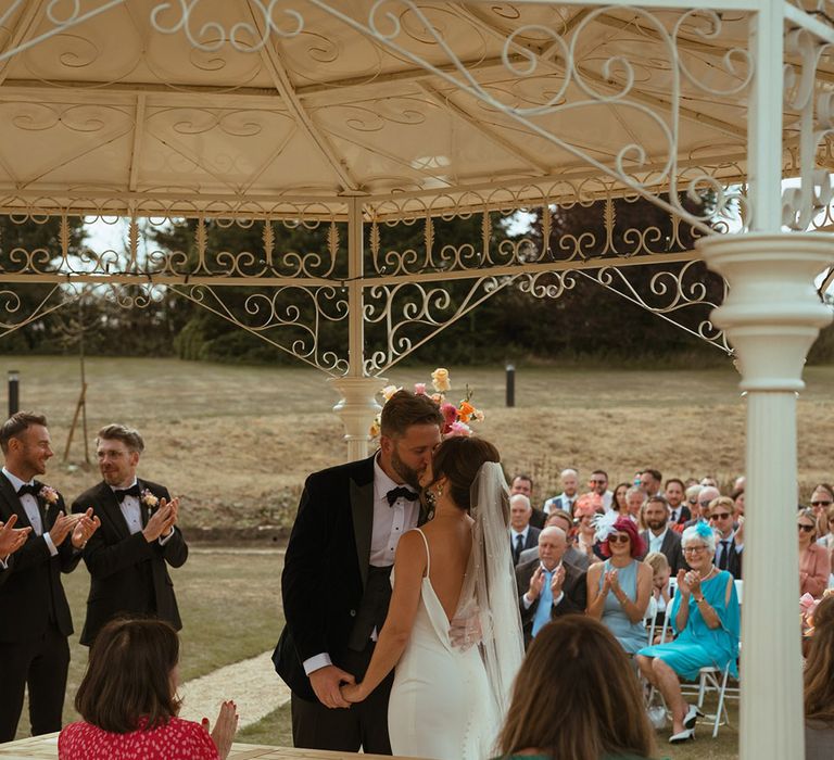 The bride and grooms share their first kiss as a married couple at their outdoor ceremony at The Pear Tree Purton 