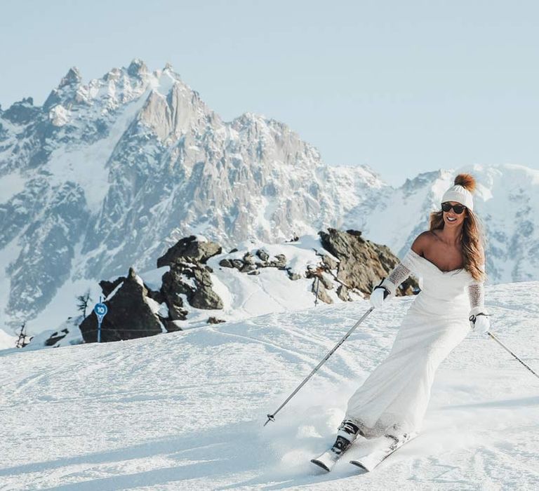 Bride in off shoulder sparkly mermaid wedding dress, wooly bobble hat and sunglasses skiing on the French Alps for ski wedding