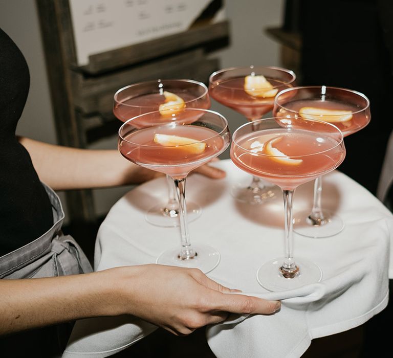 Pink wedding cocktail drinks with orange peel for wedding guests 