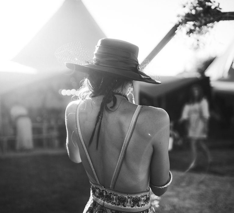 Bride in backless backless boho wedding dress and boho hat at tipi wedding venue