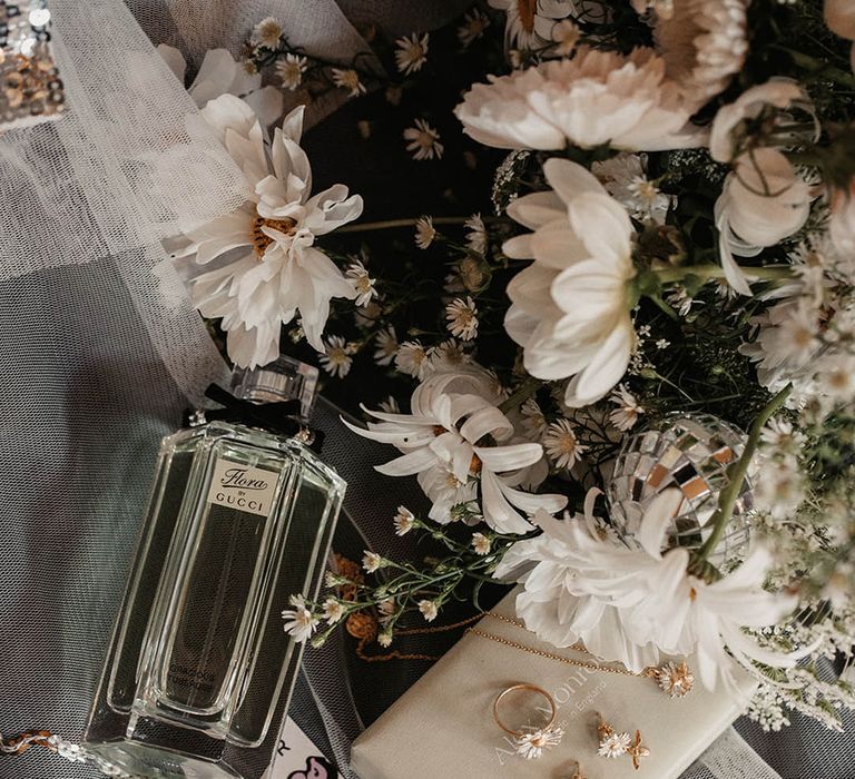 Flora by Gucci wedding perfume next to wildflower bouquet and daisy jewellery 