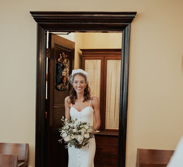 Bride in a separates and wedding headband walking in to her intimate town hall wedding ceremony 