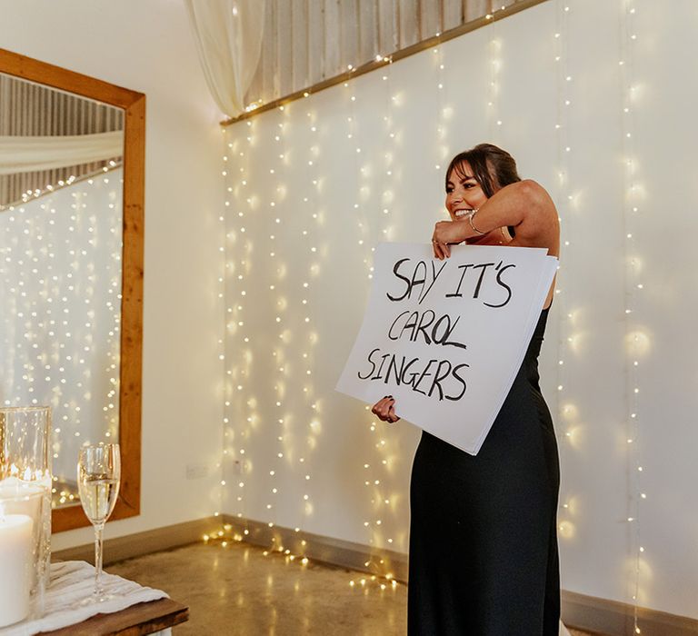 The maid of honour in a black satin bridesmaid dress reads out her wedding speech in Love Actually style 