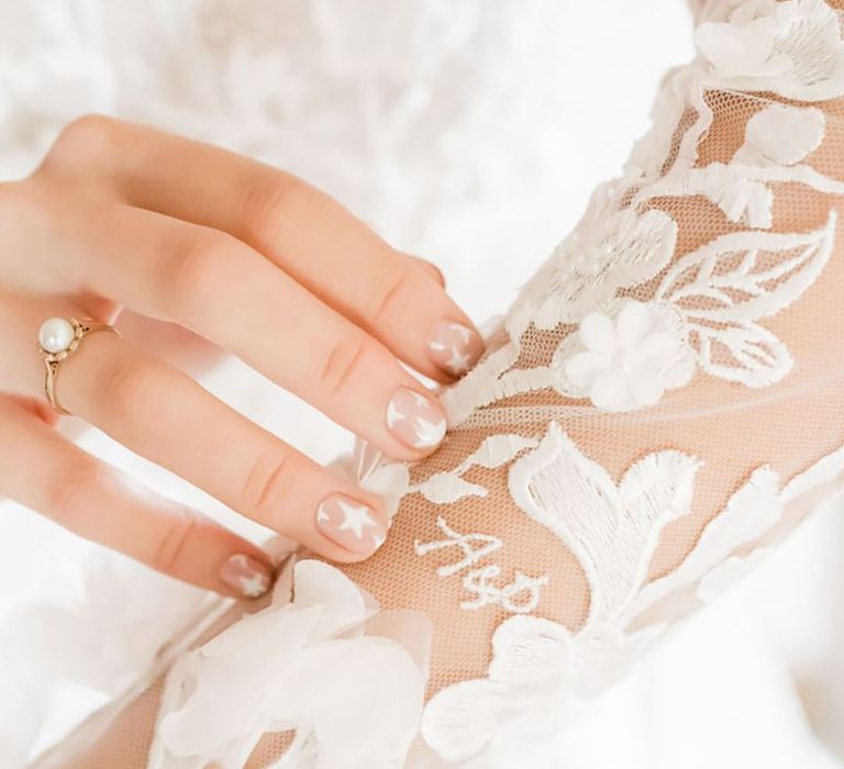 White star nail art by nail technician for bride on her wedding day wearing a long sleeve lace wedding dress 