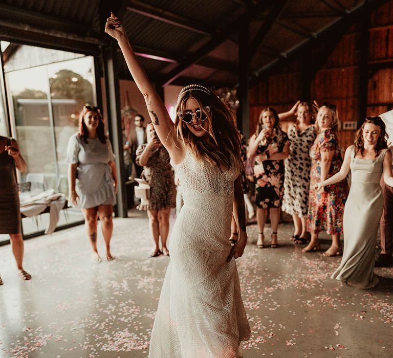 Bride in a lace wedding dress dancing in the centre of the crowd at the wedding reception 