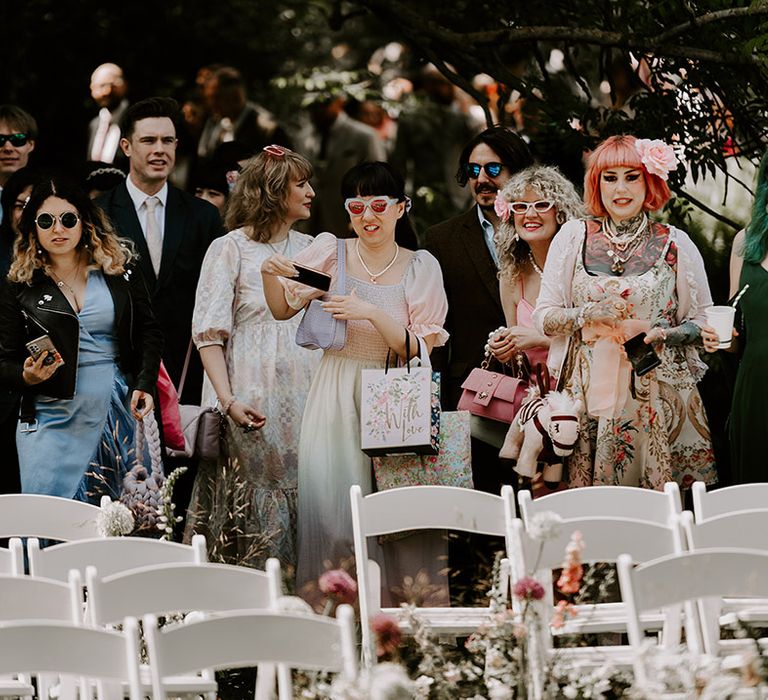 Wedding guests wearing bright and pastel wedding fashion walking to their seats 