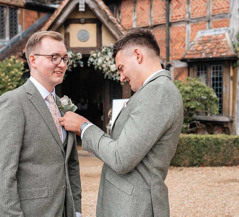 Groomsmen fixes on the groom's buttonhole for the wedding 