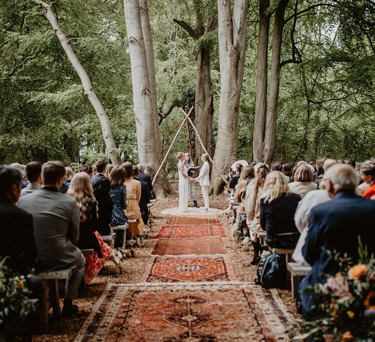 Wellington Wood outdoor wedding ceremony decorated with boho wedding flowers and Persian rugs 