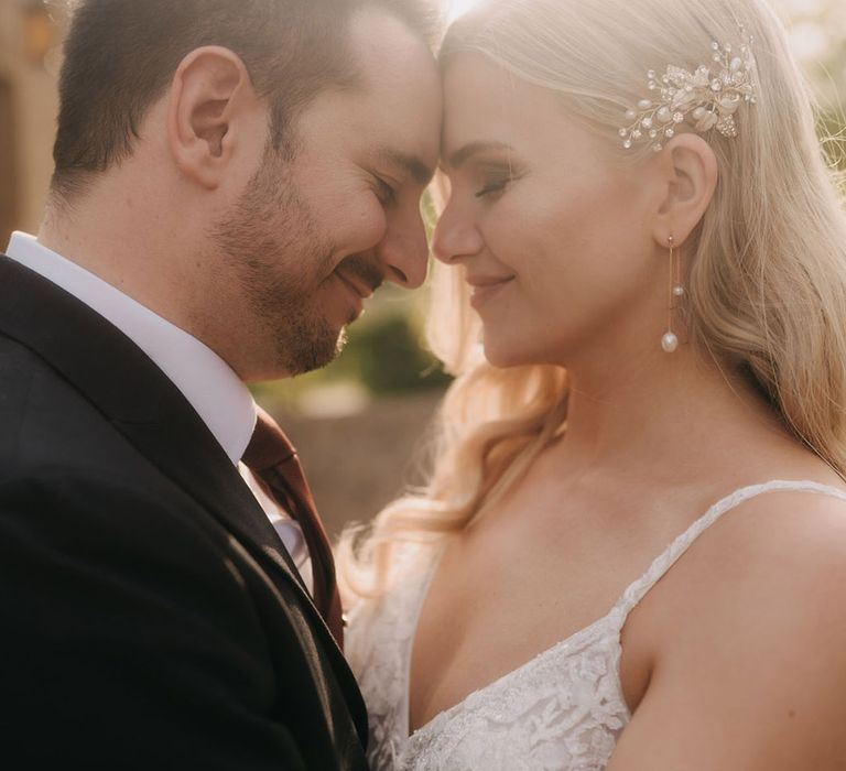 Golden hour portrait of bride and groom resting their foreheads against each other 