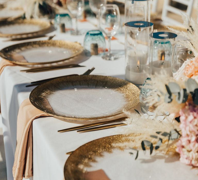 White and gold glitter charger plates for place settings with pampas grass and dried flower arrangements as centrepieces