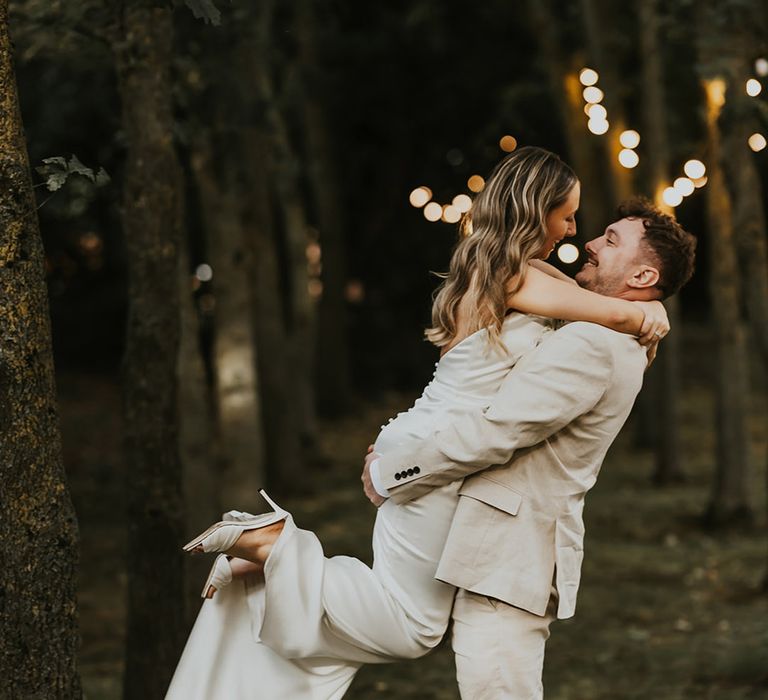 Groom in neutral wedding suit spinning the bride around for cute couple portraits 