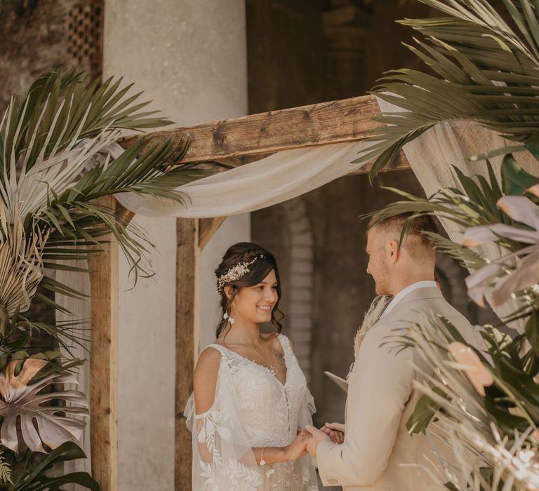 Bride and groom exchanging vows at tropical flower altar 