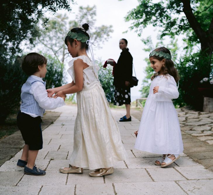 Flower girls in white dresses with foliage flower crowns 