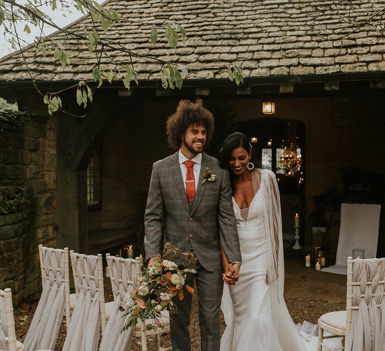 Bride and groom holding hands at their outdoor wedding ceremony 