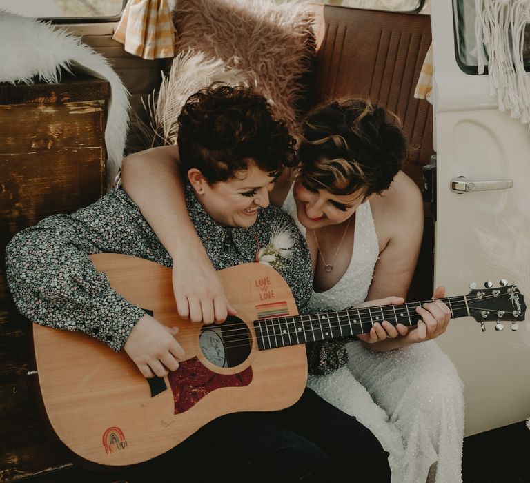 Bride and bride playing guitar in a camper van 