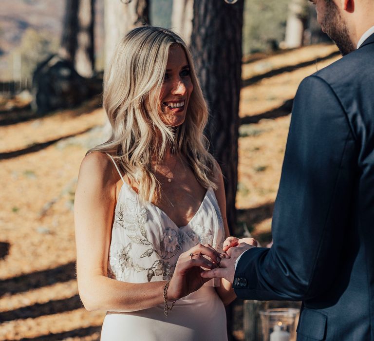 Bride places ring on groom during wedding ceremony