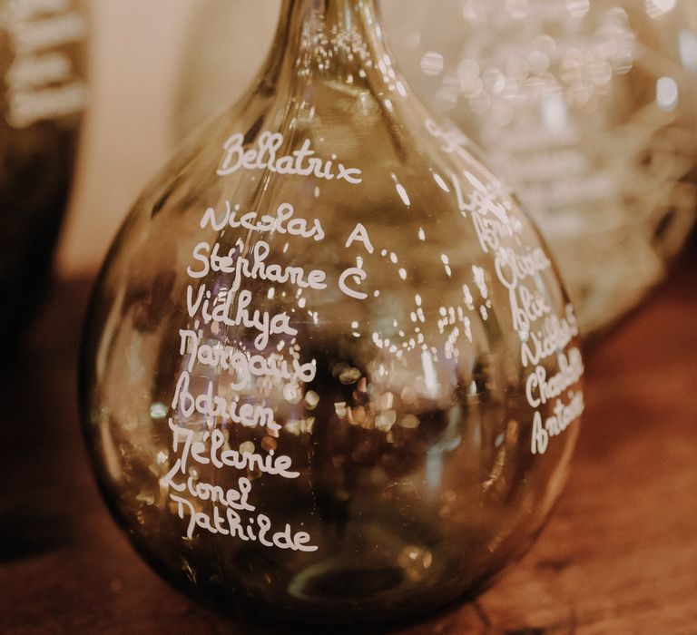 Wedding seating chart written on glass vases in white pen