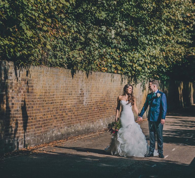 Bride and groom wedding day photography outside - bride wears fishtail ruffle dress and groom wears blue suit