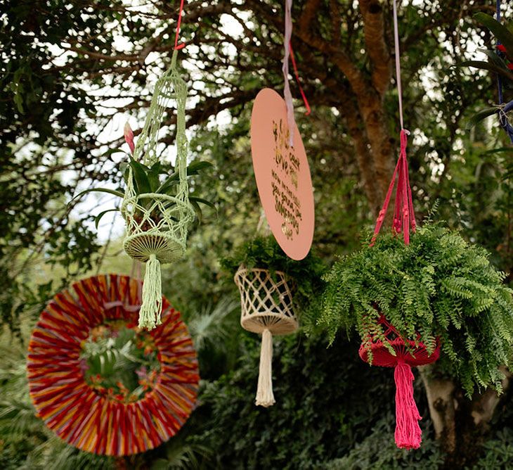 Plants and signs hang from a tree at outdoor drag race wedding inspiration shoot. Photography by Stephanie Shenton.