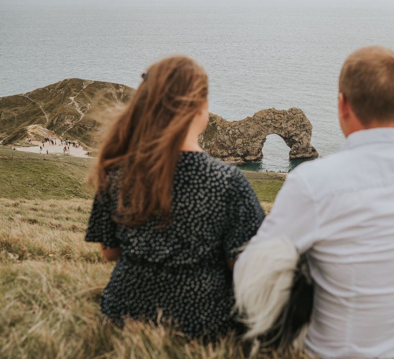 Couple sat on the beach for engagement photoshoot