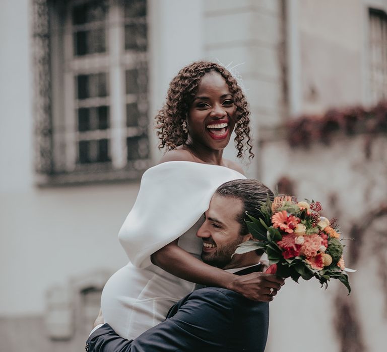 Groom lifts bride off her feet outdoors