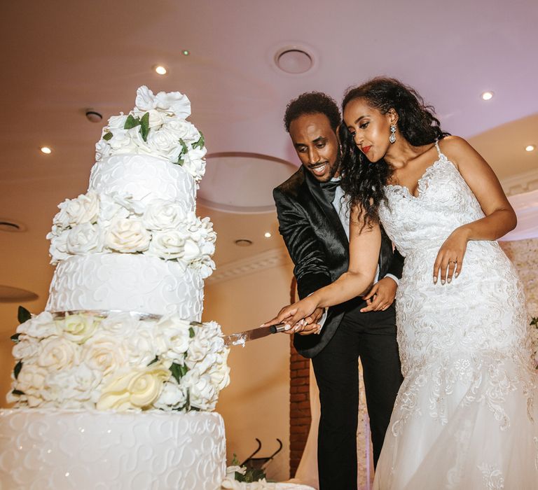 Bride and groom cutting their impressive all white wedding cake 