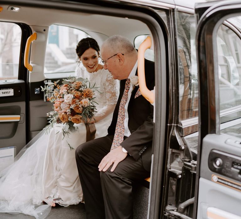 Bride with father of the bride sat in the back of black cab with peach wedding bouquet 