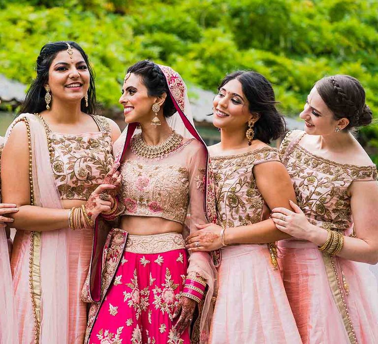 Bride in traditional Indian wedding dress with bridesmaids in pink dresses