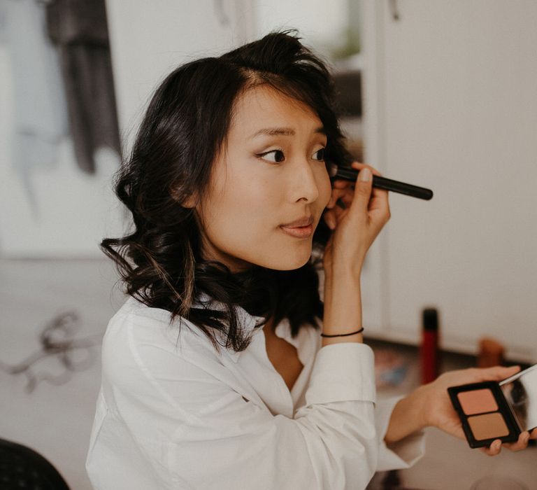 The bride applying her makeup