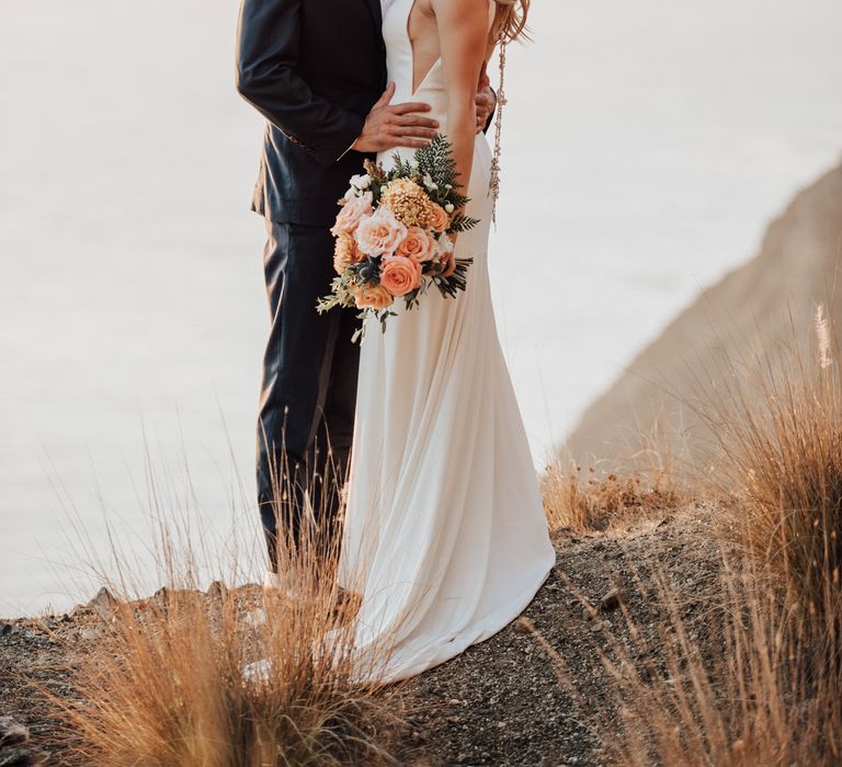 Bride & groom look at one another lovingly on their wedding day outdoors 