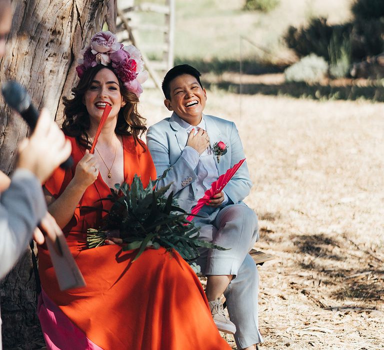 Brides listen during wedding ceremony as they sit together