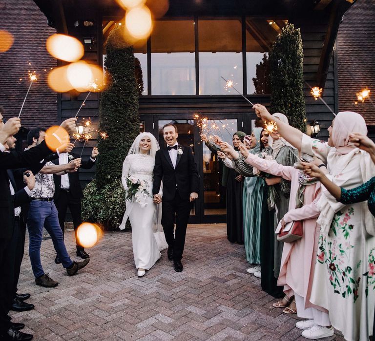 Bride and groom walk together as the wedding guests give them a sparkler send off