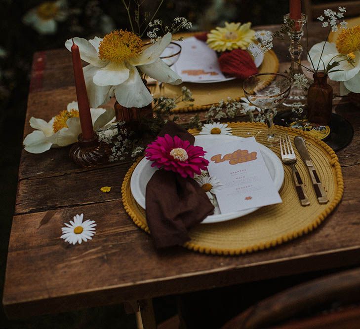 Place setting with round yellow placemats, gold cutlery and retro on the day stationery 