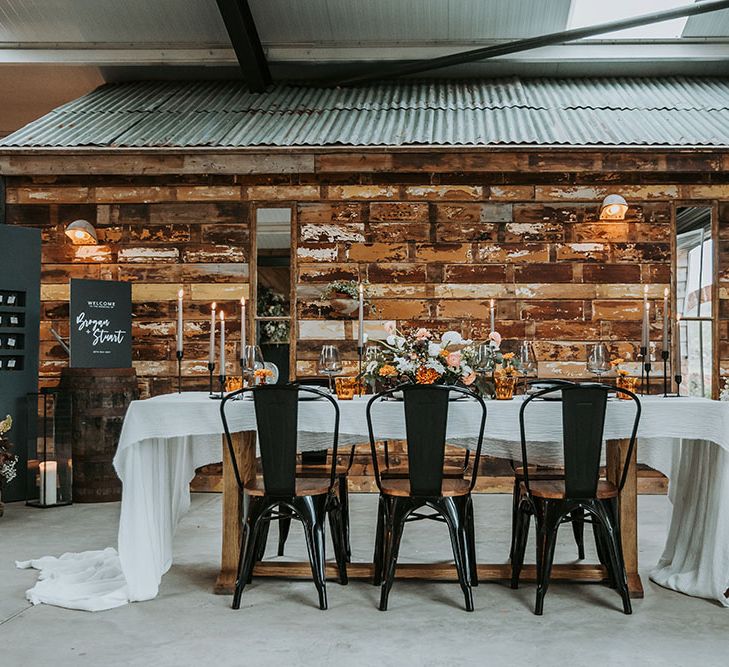 Contemporary wedding reception decor at new Lake District wedding venue, Ghyll Barn with black stationery and signs, orange and white flowers and decor