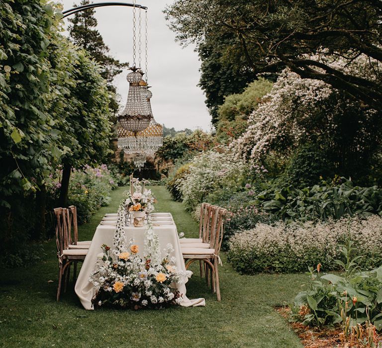 Outdoor wedding reception at Barnsley House gardens with chandelier light installation, floral arrangements and taper candles 