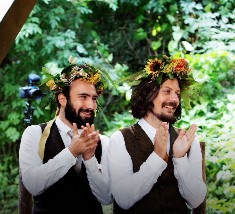 Grooms smile and clap whilst wearing floral crown on their wedding day