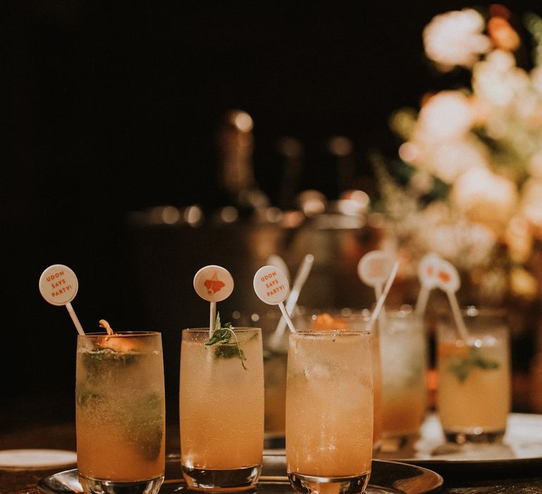 Tray of signature orange cocktails with bespoke stirrers 