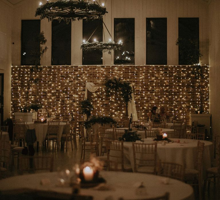 Wedding breakfast room at East Afton Farmhouse with round tables, bamboo chairs and lit by fairy lights with macrame wedding decor