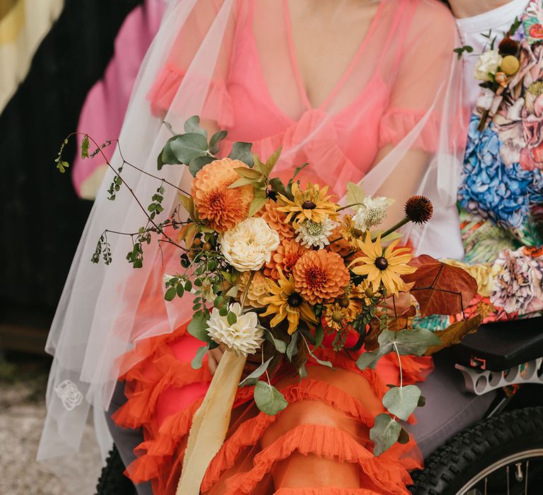 Coral layered tulle wedding dress and yellow and orange dahlia bouquet 