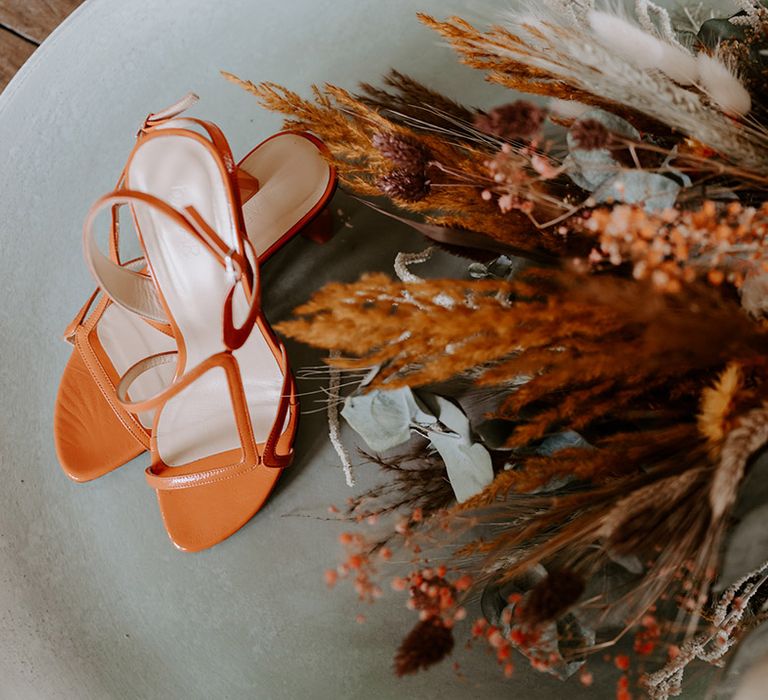 Orange wedding shoes and dried flower wedding bouquet 