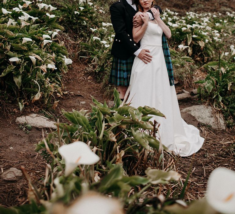 Scottish wedding inspiration with groom in a kilt embracing his red headed bride in a princess wedding dress