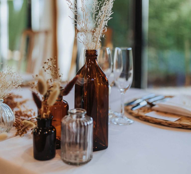 Dried flower table decoration in amber bottles and glasses