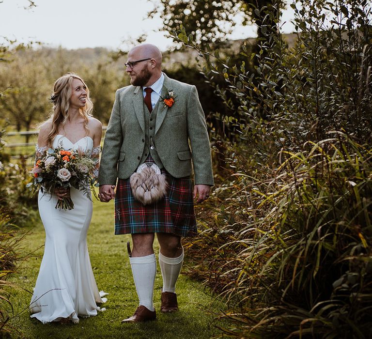 Bride & groom walk with one another as groom wears vegan sporran 