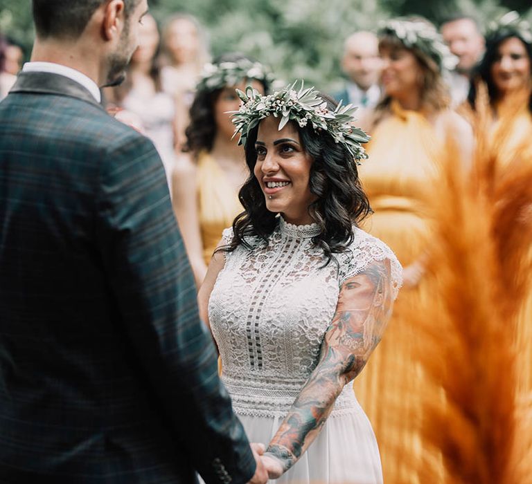 Bride wears floral crown on her wedding day and looks lovingly at her groom