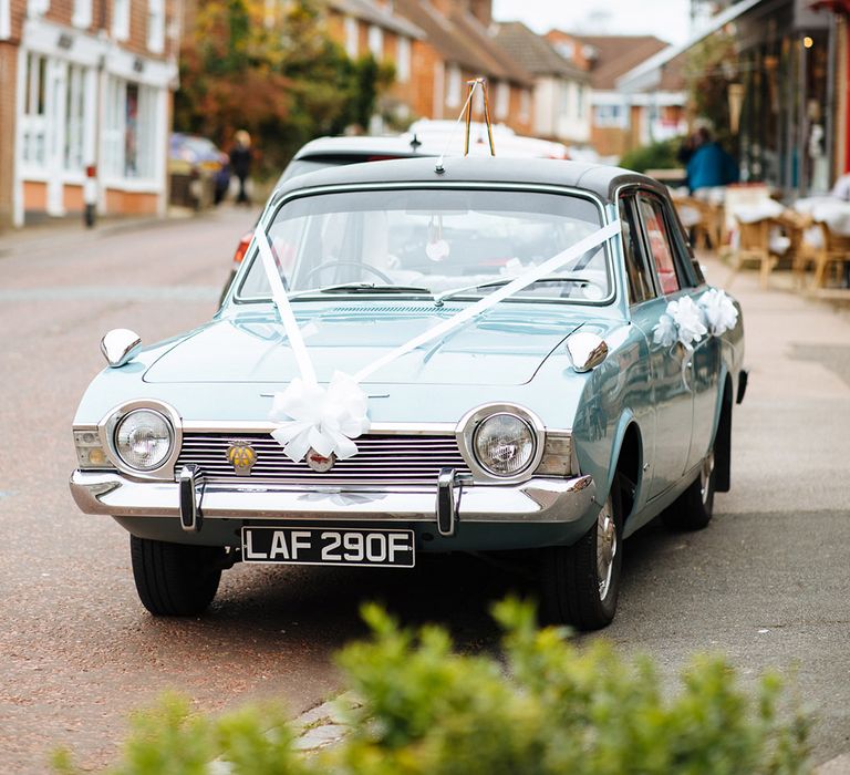 Vintage baby blue wedding car transportation with white ribbon and bows 