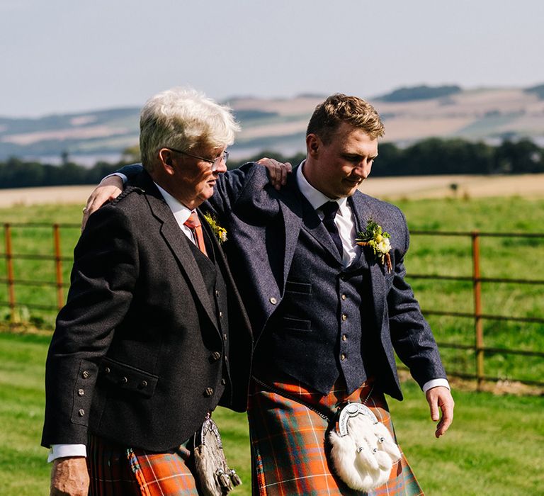 Groom with father on wedding day in matching family kilts for country house wedding