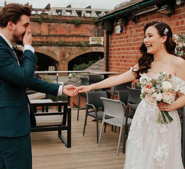 Groom in blue suit tears up as he gets his first look at the bride in lace flower sweetheart off the shoulder wedding dress 