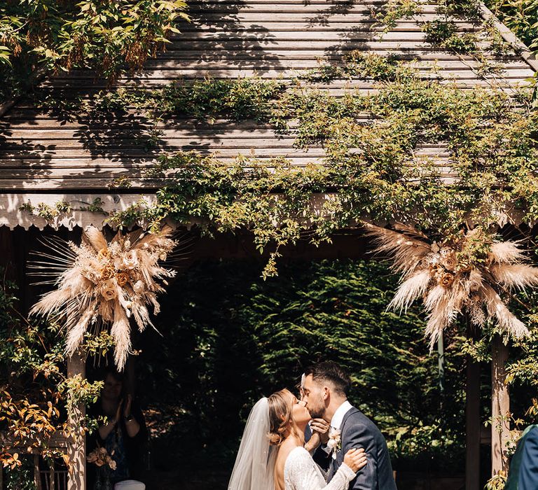 Bride and groom share their first kiss as a married couple for outdoor wedding ceremony at Pennard House